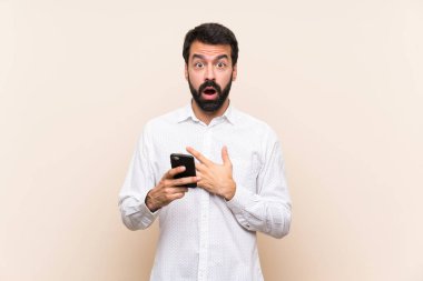 Elinde cep telefonu olan sakallı genç adam sağa bakarken şaşırdı ve şok oldu.