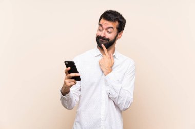 Sakallı genç adam cep telefonu kullanıyor ve bir mesaj gönderiyor.