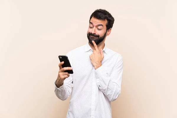 Ung Mann Med Skjegg Som Holder Mobil Tenkning Sender Beskjed – stockfoto