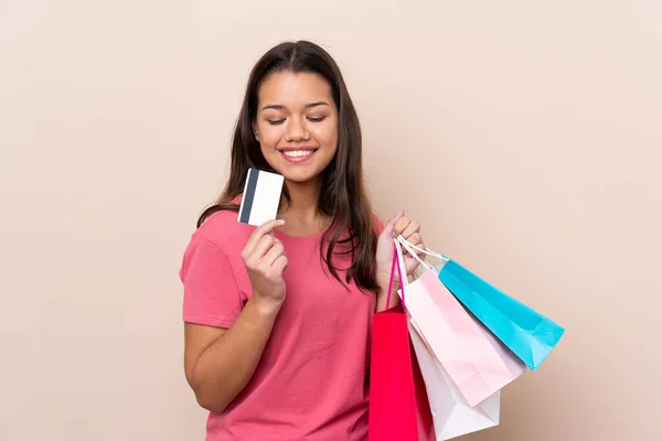 若いですコロンビアの女の子とともにショッピングバッグ上の隔離された背景保持ショッピングバッグとクレジットカード — ストック写真