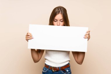 İzole edilmiş arka planda genç sarışın bir kadın bir konsept eklemek için beyaz bir levha tutuyor.