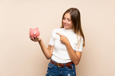 Tecrit edilmiş genç sarışın kadın elinde büyük bir kumbara tutuyor.