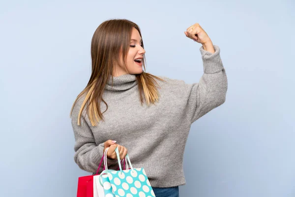 Adolescente Avec Pull Sur Fond Bleu Isolé Tenant Beaucoup Sacs — Photo