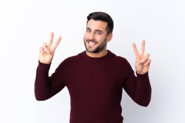 Sakallı yakışıklı genç adam izole edilmiş beyaz arka planda iki eliyle zafer işareti gösteriyor.