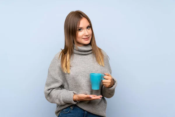 Teenagerka Svetrem Přes Izolované Modré Pozadí Horkou Šálkou Kávy — Stock fotografie