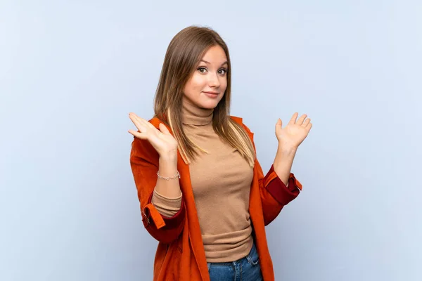 Ragazza Adolescente Con Cappotto Sfondo Blu Isolato Facendo Dubbi Gesto — Foto Stock