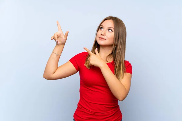 Teenager Mädchen Über Isoliertem Blauem Hintergrund Zeigt Mit Dem Zeigefinger — Stockfoto
