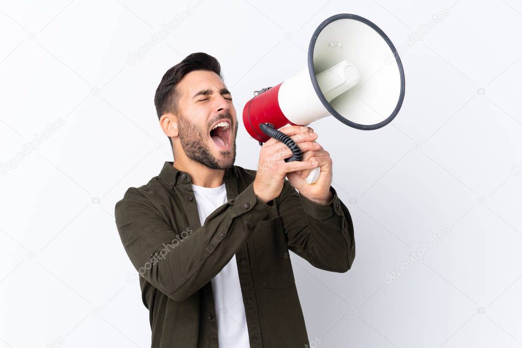 Young handsome man with beard over isolated white background shouting through a megaphone