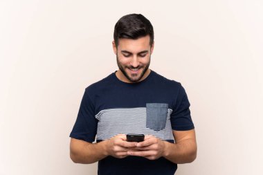 Sakallı, sakallı, genç ve yakışıklı bir adam cep telefonuyla mesaj yolluyor.