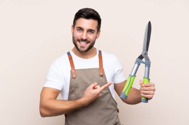 Bahçıvan arka planda budama makası tutuyor.