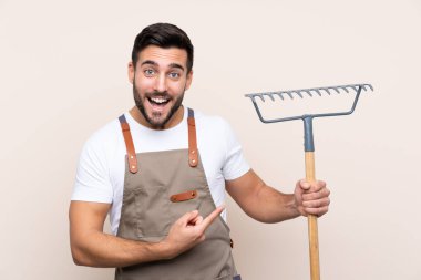 Bahçıvan arka planda bir tırmık tutuyor.
