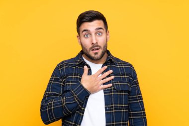 Sarı arka planda sakallı yakışıklı genç adam sağa bakarken şaşırdı ve şok oldu.