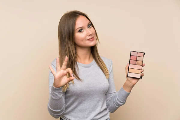 Chica Adolescente Con Paleta Maquillaje Sobre Fondo Aislado Mostrando Signo — Foto de Stock