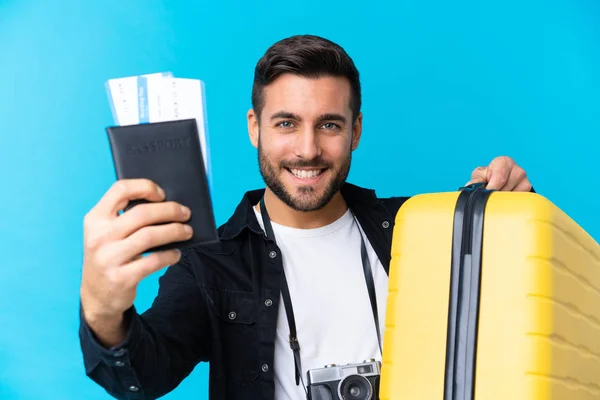 Viajante segurando uma mala e um passaporte sobre blu isolado — Fotografia de Stock