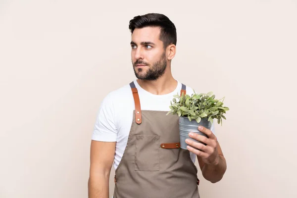 Jardineiro Homem Segurando Uma Planta Sobre Fundo Isolado Olhando Lado — Fotografia de Stock