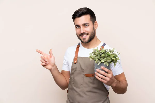 Jardinero Hombre Sosteniendo Una Planta Sobre Fondo Aislado Señalando Dedo —  Fotos de Stock