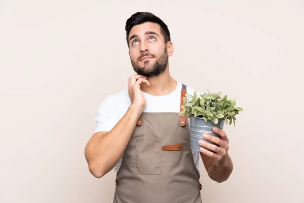 Jardinero Hombre Sosteniendo Una Planta Sobre Fondo Aislado Pensando Una —  Fotos de Stock