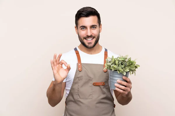 Jardinero Hombre Sosteniendo Una Planta Sobre Fondo Aislado Mostrando Signo —  Fotos de Stock