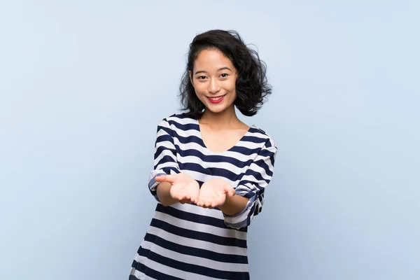 Asiática Jovem Mulher Sobre Isolado Fundo Azul Segurando Copyspace Imaginário — Fotografia de Stock