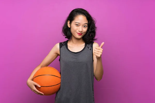 Fiatal ázsiai nő kosárlabdázni át elszigetelt lila háttér — Stock Fotó
