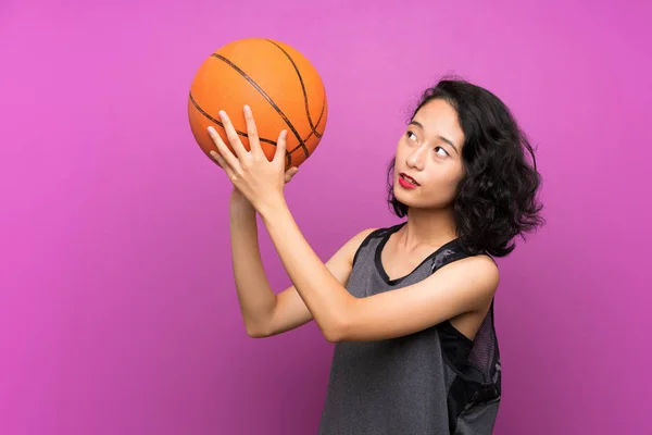 孤立した紫色の背景の上にバスケットボールをしている若いアジアの女性 — ストック写真