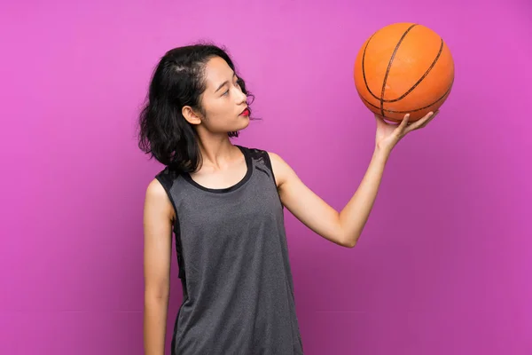 Wanita Asia muda bermain basket dengan latar belakang ungu yang terisolasi — Stok Foto