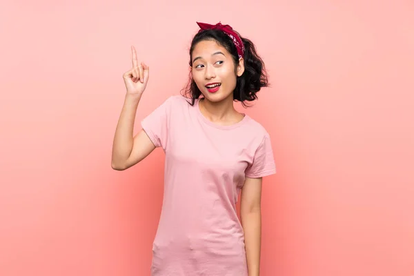 亚洲的年轻女子在孤立的粉色背景上 想在举起一只手指头的同时实现这个解决方案 — 图库照片