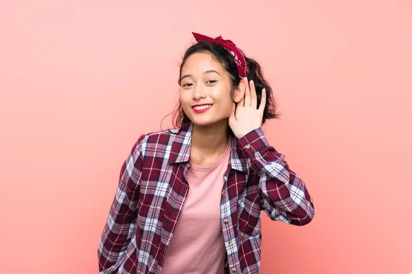 亚洲年轻女子在孤立的粉红色背景听的东西 把手放在耳朵上 — 图库照片