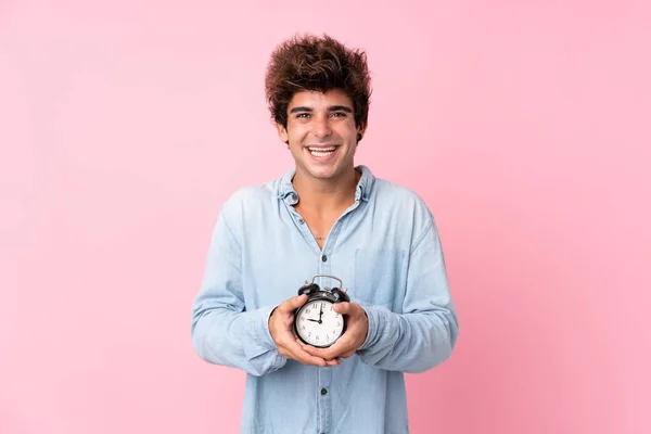 年轻的高加索人男子拿着老式闹钟在孤立的粉色背景上 — 图库照片