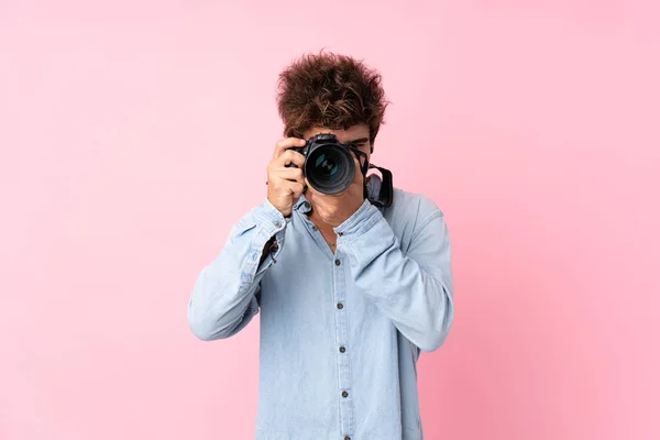 Jovem Caucasiano Sobre Fundo Rosa Isolado Com Uma Câmera Profissional — Fotografia de Stock