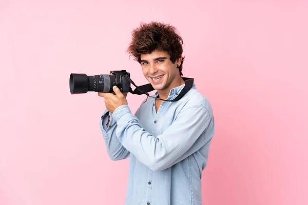 Jovem Caucasiano Sobre Fundo Rosa Isolado Com Uma Câmera Profissional — Fotografia de Stock