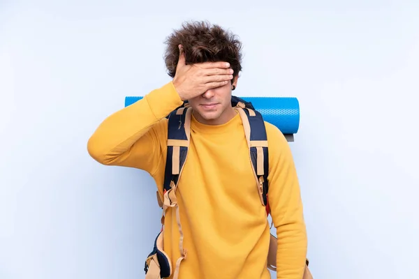 Joven Montañero Con Una Gran Mochila Sobre Fondo Azul Aislado — Foto de Stock