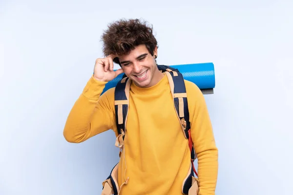 Joven Montañero Con Una Gran Mochila Sobre Fondo Azul Aislado — Foto de Stock