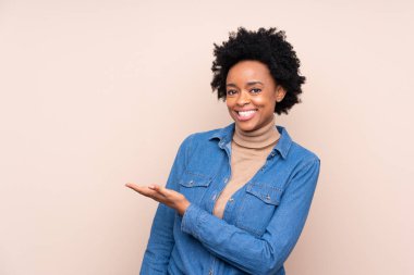 Afrika kökenli Amerikalı bir kadın, izole edilmiş arka planda, davet edildiği için ellerini yana uzatıyor.