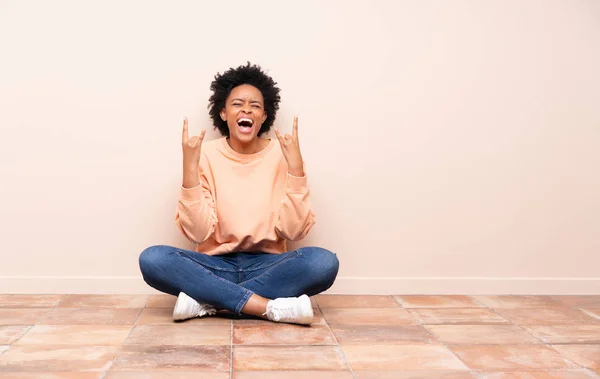 Africano Americano Mulher Sentada Chão Fazendo Gesto Rocha — Fotografia de Stock