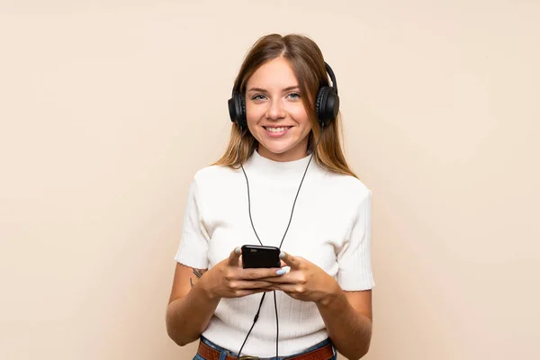 Νεαρή Ξανθιά Γυναίκα Πάνω Από Απομονωμένη Φόντο Χρησιμοποιώντας Κινητό Ακουστικά — Φωτογραφία Αρχείου