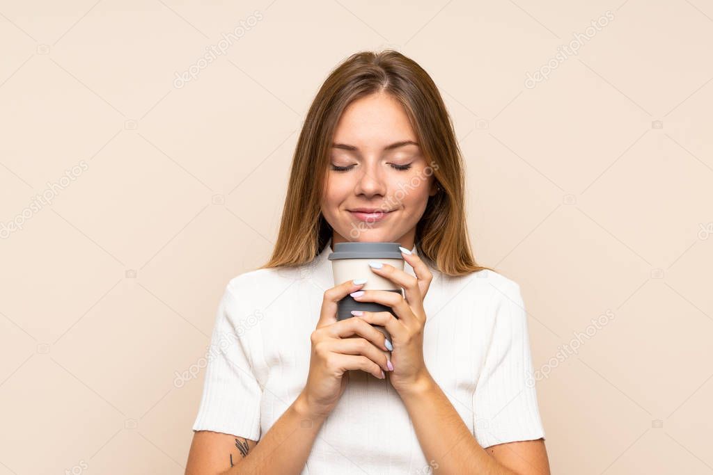 Young blonde woman over isolated background holding coffee to take away