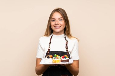 Sarışın bir kadın, izole edilmiş arka planda mini pastalar tutuyor.