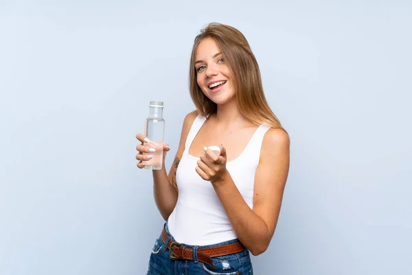 Giovane ragazza bionda con una bottiglia d'acqua su sfondo isolato — Foto Stock