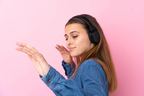 Adolescente chica escuchando música y bailando sobre aislado rosa wal — Foto de Stock