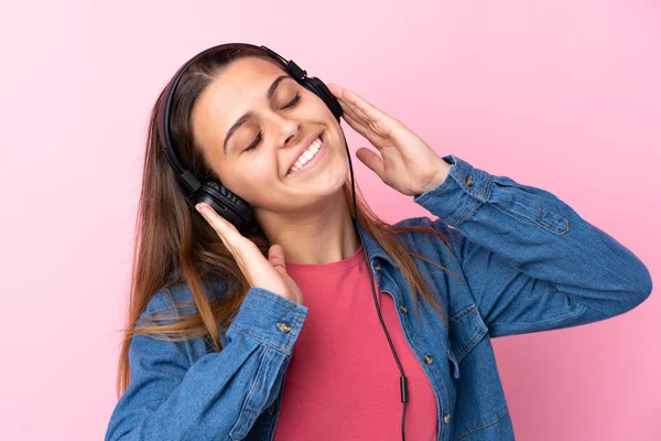 Adolescente chica escuchando música y bailando sobre aislado rosa wal — Foto de Stock