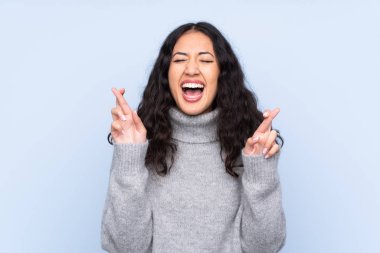 İspanyol Çinli kadın izole edilmiş mavi arka planda şans diliyor.