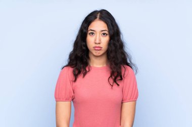 Melez ırktan bir kadın, mavi arka planda bir süveter giyiyor.