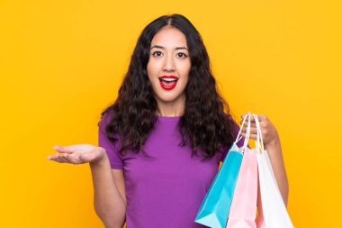 Alışveriş çantalı İspanyol kadın izole edilmiş bir arka plan ve şok olmuş yüz ifadesi.