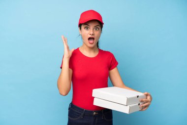 Genç kadın sürpriz yüz ifadesi ile izole pembe duvar üzerinde bir pizza tutan