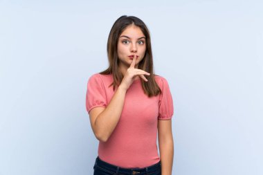 Genç esmer kız soyutlanmış mavi arka planda sessizlik hareketi yapıyor.