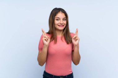 Genç esmer kız izole edilmiş mavi arka planda parmakları çapraz