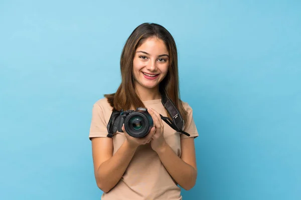 Chica Morena Joven Sobre Fondo Azul Aislado Con Una Cámara —  Fotos de Stock