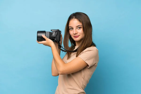 Jovem Morena Sobre Fundo Azul Isolado Com Uma Câmera Profissional — Fotografia de Stock