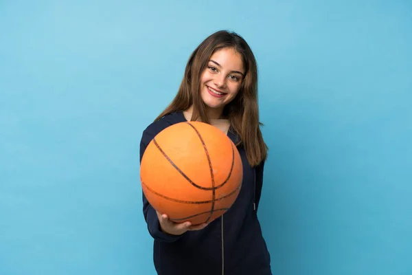 一个年轻的黑发女孩带着篮球运动越过了孤立的蓝色背景 — 图库照片